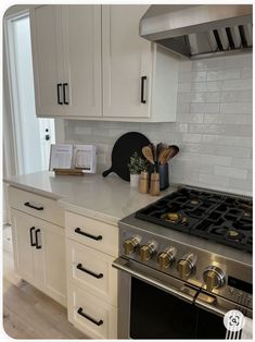 a stove top oven sitting inside of a kitchen next to white cabinets and counter tops