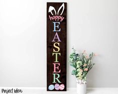 a wooden sign that says happy easter next to a potted plant and vase with flowers