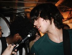 a man singing into a microphone while standing next to another man