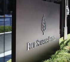 the four seasons hotel sign is in front of some bushes and grass on the sidewalk