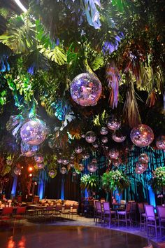 a room filled with lots of disco balls and plants hanging from it's ceiling