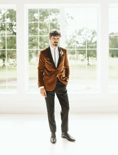 a man in a tuxedo poses for the camera with his hands in his pockets