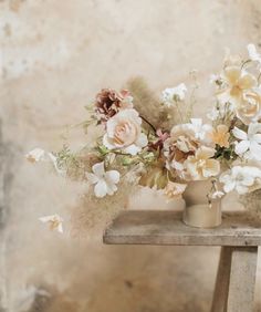 a vase filled with flowers sitting on top of a wooden table next to a wall