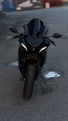 a black motorcycle parked on the street in front of a parking lot with no one around it