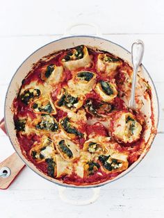 a pizza sitting on top of a pan covered in cheese and spinach toppings