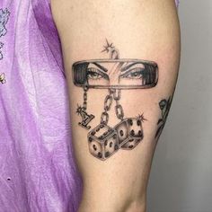 a woman's leg with a tattoo on it that has dices and chains attached to the legs