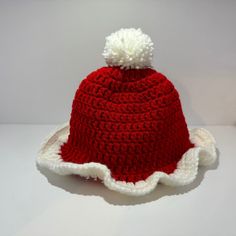 a red and white crocheted hat with a pom - pom on top