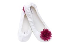 pair of white ballet shoes with pink flower on the soles, isolated against white background