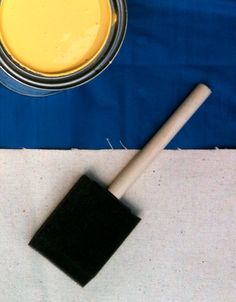 a paint can with a brush next to it on a blue and white table cloth