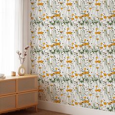 the wallpaper is decorated with yellow flowers and green stems on white walls, along with a wicker sideboard