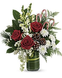 a christmas bouquet with red roses, white flowers and candy canes in a green vase