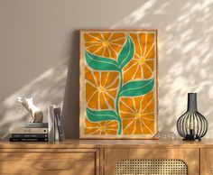 an orange and green art piece sitting on top of a wooden dresser next to a lamp