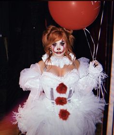 a woman dressed as a clown holding a red balloon