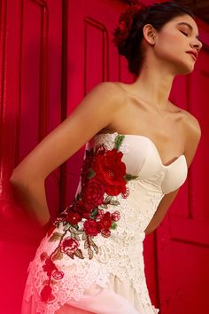 a woman in a white dress with red flowers on her corset is posing for the camera