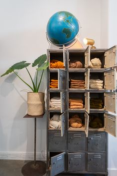 an old metal storage unit with clothes and a globe on top