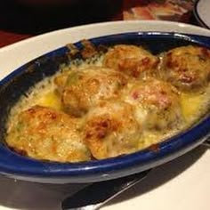 a blue bowl filled with food on top of a white table next to a fork