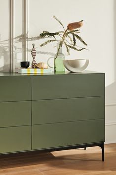 a green dresser with a bowl and vase on top