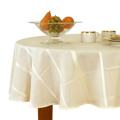 a bowl of fruit sitting on top of a table next to two cups and saucers