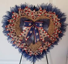 a heart shaped wreath with red, white and blue decorations hanging on a door way