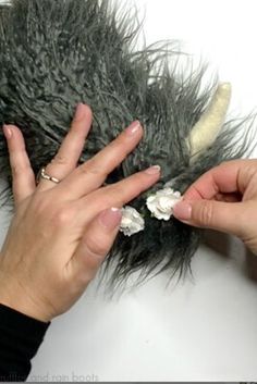 two hands are holding something that looks like an animal's fur