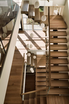 an overhead view of a staircase with glass balconies and wooden handrails