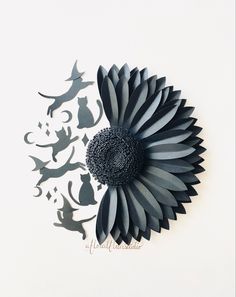 a paper cut flower with cats and birds in the background, on a white surface