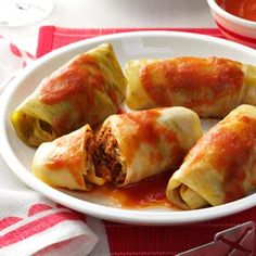 stuffed cabbage rolls on a white plate with sauce