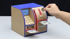 an atm machine made out of cardboard with money coming out of the front and side