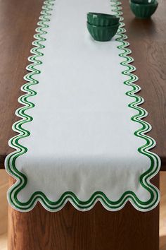 a table that has some green bowls on it and a white table cloth with green trim