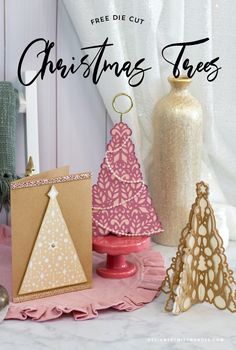 christmas trees are on display in front of a white curtain and pink table cloth with gold ornaments