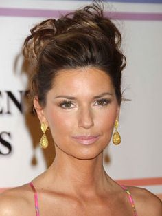 a woman in a pink dress with gold earrings on her head and hair pulled back into a bun