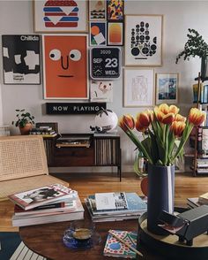 a living room filled with lots of pictures and flowers in a vase on top of a coffee table