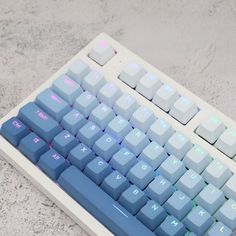 a computer keyboard sitting on top of a white table next to a blue and pink key board