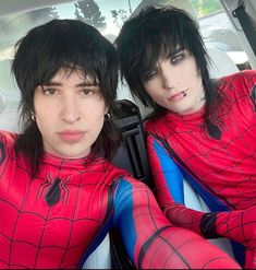 two people in spider man costumes sitting in the back seat of a car with their hands on their hips