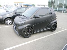 a smart car parked in a parking lot next to other cars