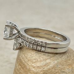 two wedding rings sitting on top of a rock next to each other, with one diamond in the middle