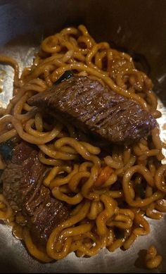 beef and noodles are being cooked in a wok