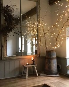 a candle is lit in front of a mirror with branches and lights on the wall