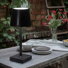 the table is set with plates, bowls and flowers in vases next to it