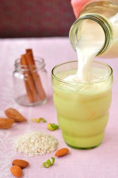 a person pouring milk into a glass filled with rice