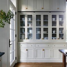 a kitchen with white cabinets and wood floors