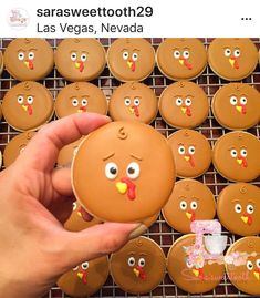 a person holding a cookie in front of a rack of cookies with faces on them