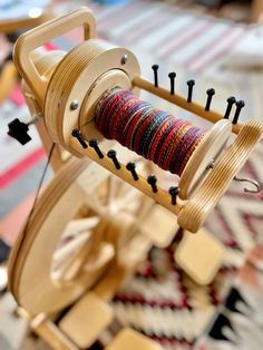 a wooden spinning machine with several different colored thread spools