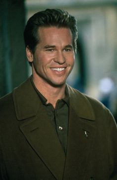 a smiling man in a brown jacket and black shirt