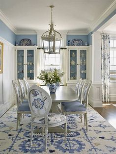 a dining room table with blue and white china on the wall behind it, surrounded by chairs