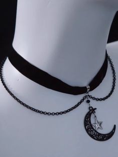 Embrace celestial elegance with our Moon and Star Pendant Velvet Choker. Crafted from luxurious black velvet, this choker features moon and star pendants that shimmer with every movement. The design is further elevated with delicate chain accents, adding a touch of edgy sophistication. Celestial Choker, Black Crescent Celestial Jewelry, Celestial Black Crescent Jewelry, Moon Choker, Black Moon Charm Jewelry For Party, Black Jewelry With Moon Charm For Party, Black Metal Moon Shaped Jewelry, Black Metal Moon-shaped Jewelry, Celestial Black Metal Jewelry