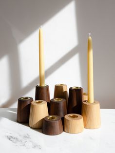 several wooden candles sitting on top of each other in front of a white wall and window