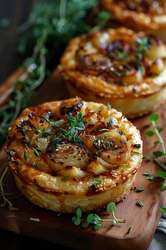 three onion tarts on a wooden cutting board with sprigs of thyling