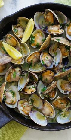 a skillet filled with clams and lemon wedges