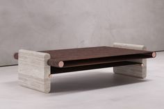 a wooden bench sitting on top of a white floor next to a gray concrete wall